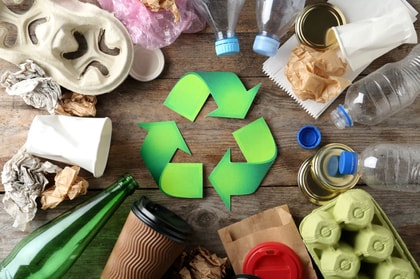 Plastik, Papier, Glasmüll liegt im Kreis auf einem Tisch in der Mitte ein Recycling Symbol 